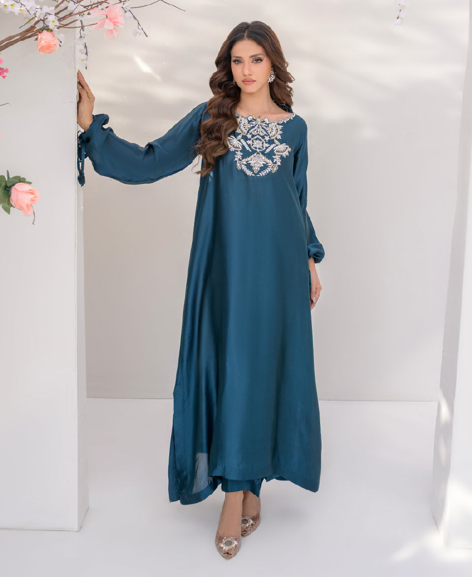 Teal sheesha silk long shirt with gold kora dabka embroidery on neckline, paired with wide-leg pants, featuring pearl and gold tassels for a luxurious festive look.
